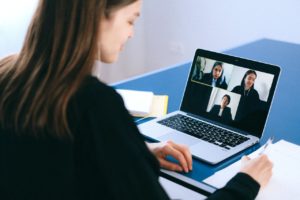 garota jovem escrevendo em papel enquanto faz chamada de vídeo com amigos