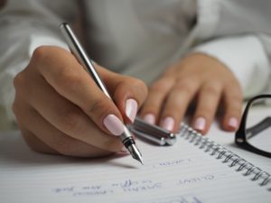 mãos femininas escrevendo com caneta em caderno