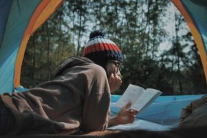 jovem fazendo leitura diária dentro de barraca em floresta