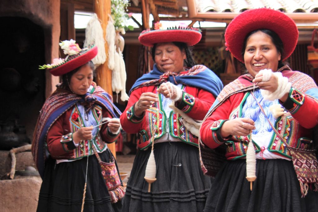 Por que estudar Geografia? Para conhecer novas culturas. Mulheres com vestidos e chapéus típicos de data comemorativa no Peru