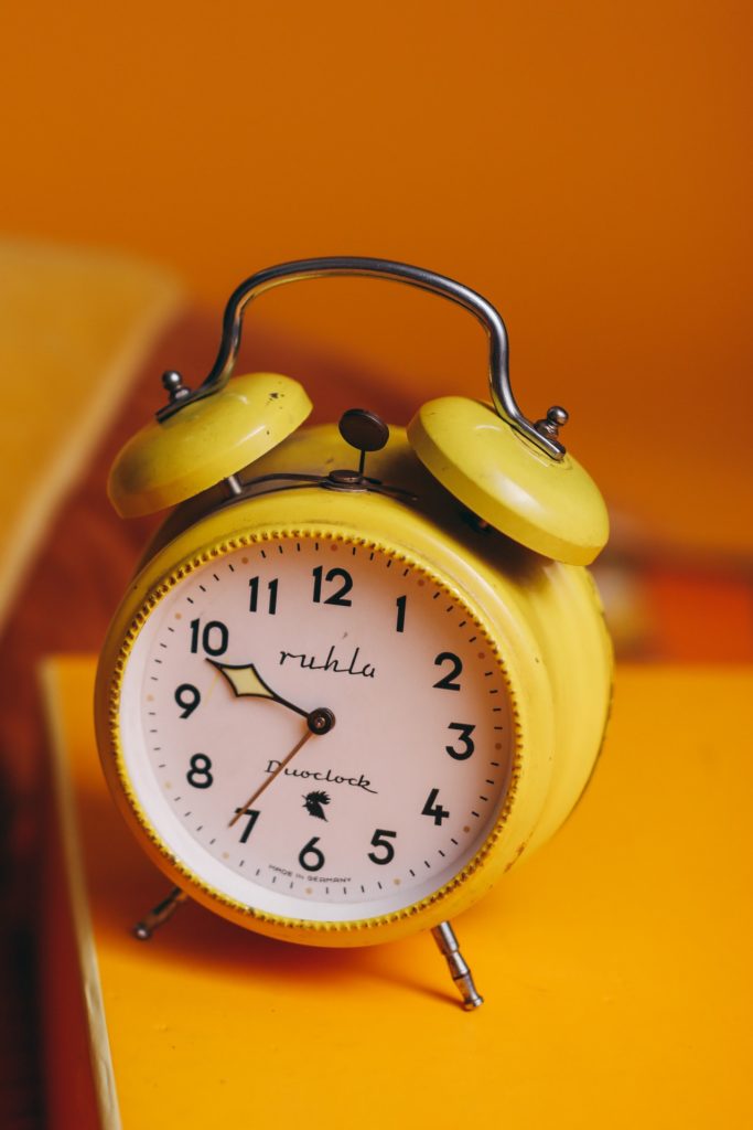 Relógio analógico amarelo com ponteiros marcando dez horas