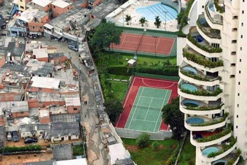 Urbanização mostrando a desigualdade social pobreza e riqueza lado a lado através de condomínio grande com quadra e favela