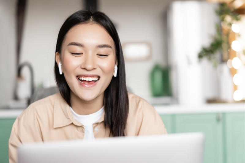 Garota japonesa sorrindo de frente a um computador